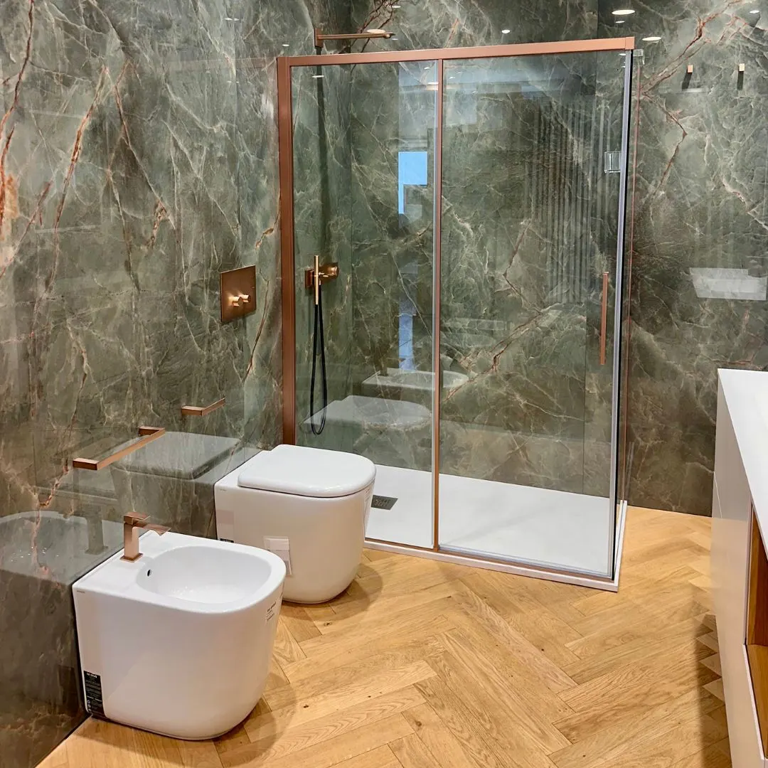 Zona doccia con rivestimento effetto marmo verde e pavimento in parquet a spina di pesce, allestita nello showroom Abitare Di Leo a Trani